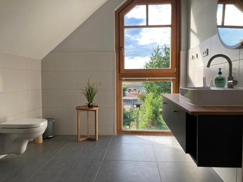 ein Bad mit einem Waschbecken, einem WC und einem Fenster in der Unterkunft Ferienhaus Pferdehof Birkholz in Bernau bei Berlin