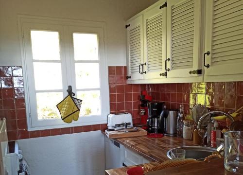 - une cuisine avec 2 fenêtres et un comptoir dans l'établissement Mas Flora, à La Croix-Valmer