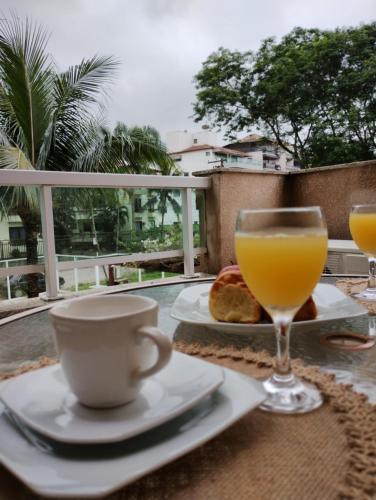 uma mesa com um copo de sumo de laranja e uma chávena em Apartamento no Hotel Porto Marina Mangaratiba em Mangaratiba