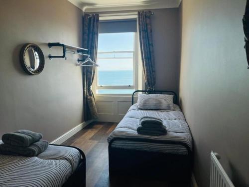 a small room with two beds and a window at Beach View Apartment - Top floor sea view Ramsgate in Ramsgate
