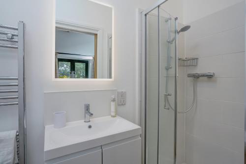 a white bathroom with a sink and a shower at Contemporary Barn Harleston Norfolk in Harleston