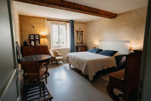 Les Granges Pelloquin في Bernières-sur-Mer: غرفة نوم بسرير وطاولة ونافذة