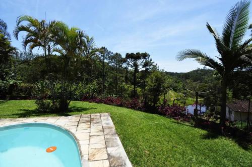a swimming pool in a yard with grass and trees at Sítio São Francisco Capacidade 30 Pessoas Juquitiba SP in Juquitiba