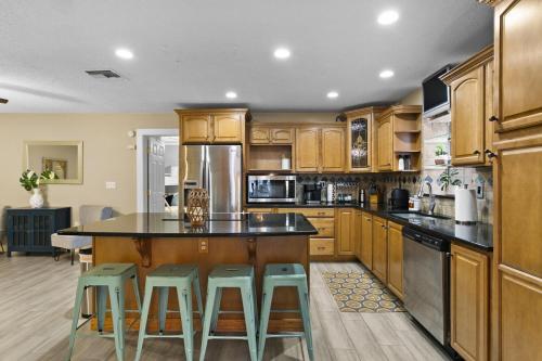a kitchen with wooden cabinets and a island with bar stools at Tropical Oasis FL Pinellas Park in Pinellas Park