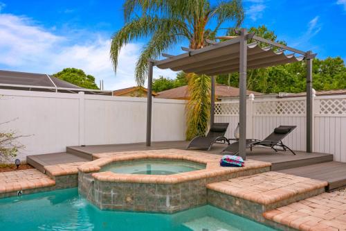 a swimming pool with a patio with two chairs and an umbrella at Tropical Oasis FL Pinellas Park in Pinellas Park