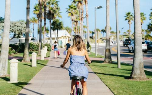 a woman in a blue dress riding a bike down a sidewalk at Tropical Oasis FL Pinellas Park in Pinellas Park