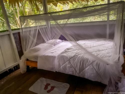 a bedroom with a bed with a mosquito net at MALOKA LODGE in Iquitos