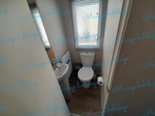 a small bathroom with a toilet and a window at Pet friendly caravan in Walton on the Naze in Walton-on-the-Naze