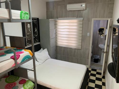 a small room with two bunk beds and a window at Hostel Mamy Dorme in Barranquilla