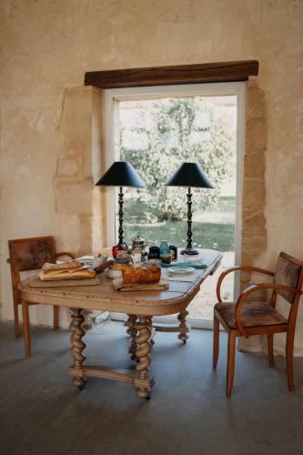 a dining room table with two lamps and a window at Les Granges Pelloquin in Bernières-sur-Mer