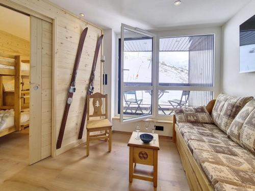 - un salon avec un canapé et des skis sur le mur dans l'établissement Charmant appartement rénové - Au pied des pistes - 4 pers - Parking - WiFi - Balcon Sud-Est - FR-1-344-871, aux Menuires