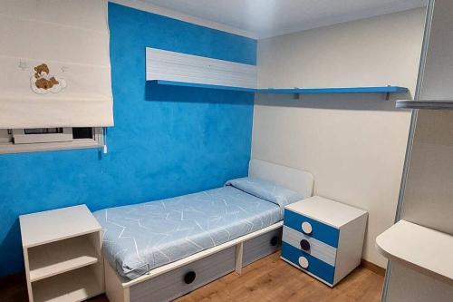 Habitación pequeña con cama y pared azul en Bravaholidays-831-Fabra-Barcelona, en Santa Coloma de Gramenet