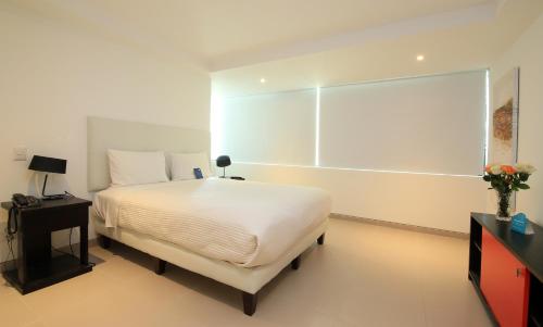 a white bedroom with a bed and a television at Edificio Poseidon Depto. Vista Lateral al Mar in Manta