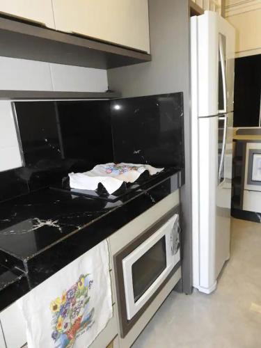 a kitchen with a black counter top and a refrigerator at Pousada Mirante do César in Bombinhas