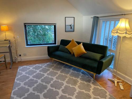 uma sala de estar com um sofá verde e uma janela em Light Airy Detached Annex 2 Min Walk Train Station em Stowmarket