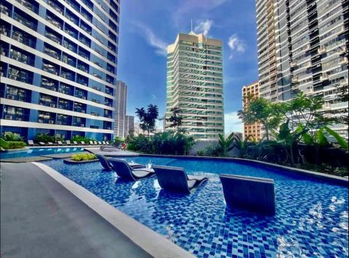 una piscina con sillas en el centro de una ciudad en Cozy Condo Apartment in Makati / Manila with mall, restaurants, groceries, pool, netflix, disney+ and more en Manila
