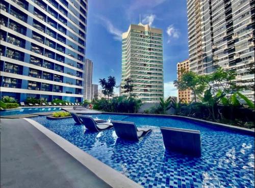 a swimming pool with chairs in the middle of a city at Cozy Condo Apartment in Makati / Manila with mall, restaurants, groceries, pool, netflix, disney+ and more in Manila
