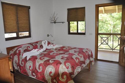 a bedroom with a bed with a red and white comforter at Hotel Piedra Marron in Las Terrenas