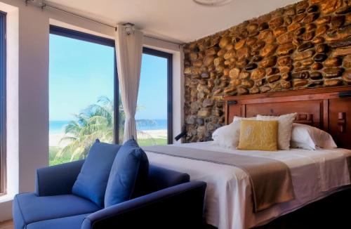 a bedroom with a large bed and a blue chair at CasaPiedra in Puerto Escondido