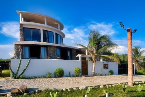 a house with a palm tree in front of it at CasaPiedra in Puerto Escondido