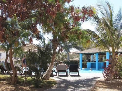 um grupo de pessoas sentadas em cadeiras sob palmeiras perto de uma piscina em Poolside Serenity at Tortuga Beach - 491 em Prainha