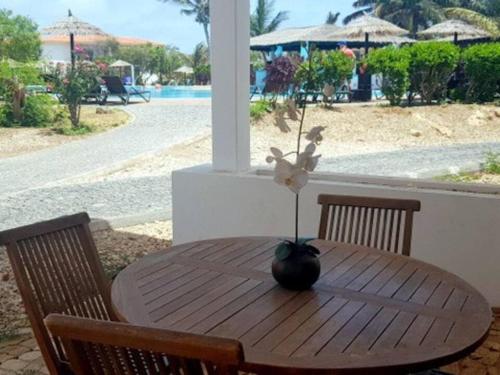 a wooden table with a vase with a flower on it at Poolside Serenity at Tortuga Beach - 491 in Prainha