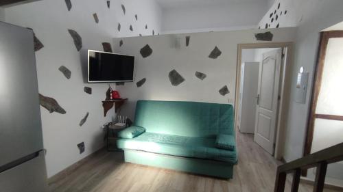 ein Wohnzimmer mit einem grünen Sofa und einem TV in der Unterkunft Vivienda Vacacional El Pajar in Breña Alta