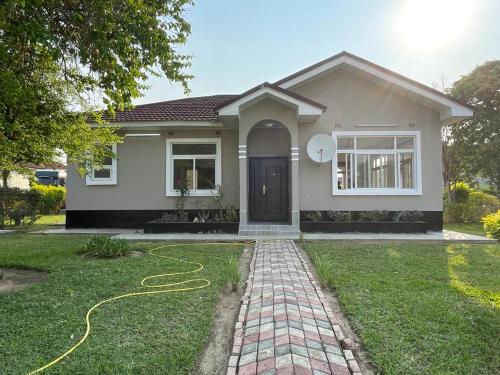a house with a yellow hose on the grass at Silverest Sanctuary: Home away from Home in Lusaka