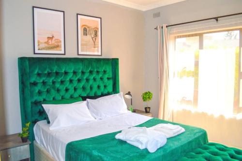 Una cama verde con dos toallas encima. en Mt Pleasant - 4-Bed Villa in Harare Solar Power en Kingsmead