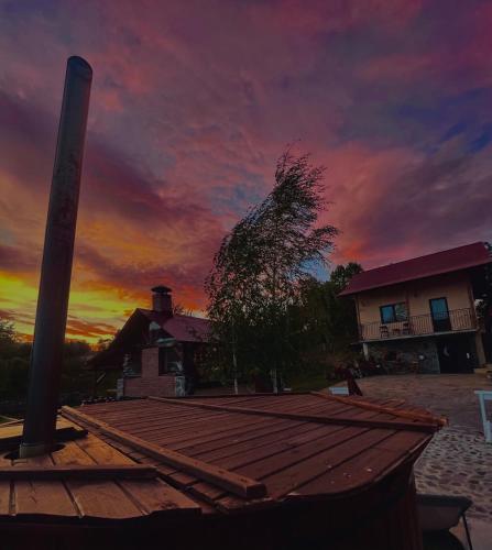 a sunset over a house with a wooden deck at Căsuța din livezi in Suceava