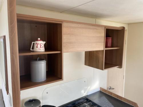 uma cozinha com armários de madeira e uma chaleira. em Captivating 2-Bed Caravan in Clacton-on-Sea em Clacton-on-Sea