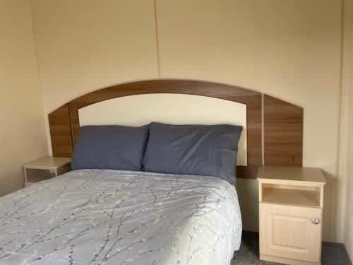 un lit avec une tête de lit en bois et 2 tables de chevet dans l'établissement Captivating 2-Bed Caravan in Clacton-on-Sea, à Clacton-on-Sea