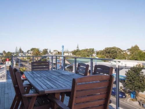 a wooden table and chairs on a balcony at Beach Pacific Apartments in Waihi Beach