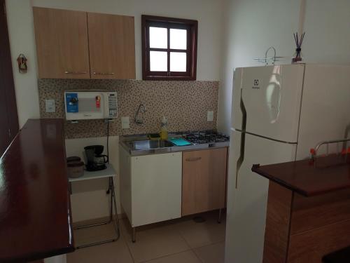 a kitchen with a white refrigerator and a sink at Flats Casa Verde in Saquarema