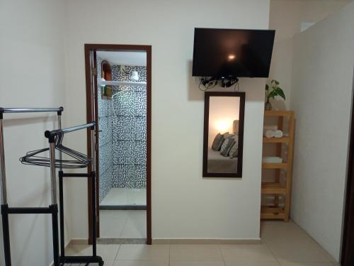 a room with a mirror and a television on a wall at Flats Casa Verde in Saquarema