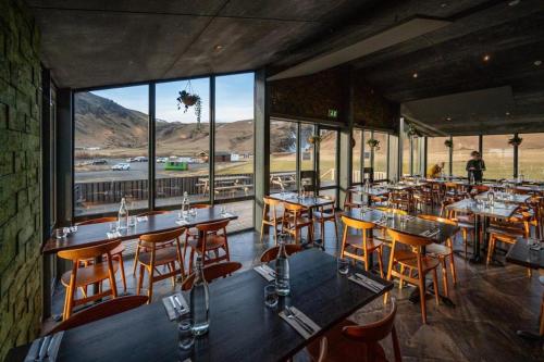 a restaurant with wooden tables and chairs and windows at Hótel Skógafoss by EJ Hotels in Skogar