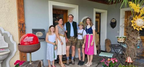 a family posing for a picture on a porch at "Hochegg" in Faistenau