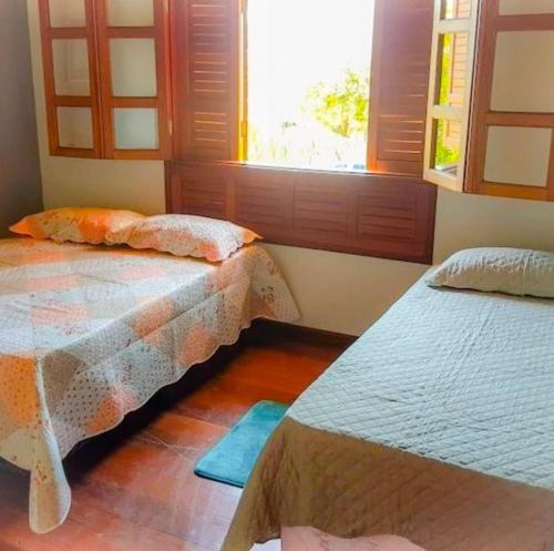 a bedroom with two beds and a window at Casa Charmosa Em Bonito in Bonito