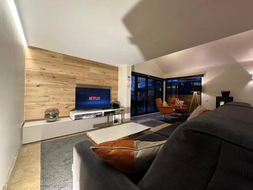 a living room with a couch and a flat screen tv at Sakura Lodging in Bossut-Gottechain
