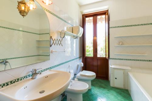 a bathroom with a sink and a toilet and a tub at Villa Donnafugata in Santa Domenica