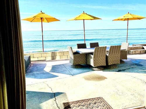 a table with chairs and umbrellas on the beach at ON THE SAND!! Private Beach! OCEAN FRONT HOT TUB!! in Dana Point