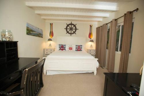 a bedroom with a large white bed with a ship wheel on the wall at ON THE SAND!! Private Beach! OCEAN FRONT HOT TUB!! in Dana Point