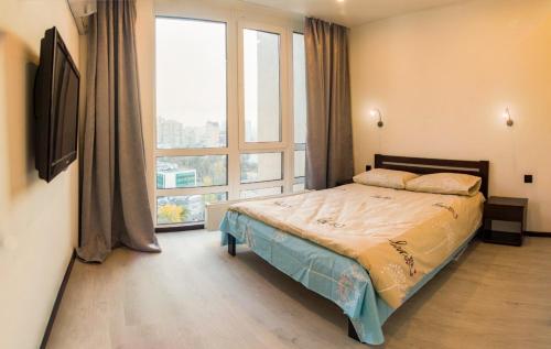 een slaapkamer met een bed en een groot raam bij Панорамные Апартаменты в новом доме in Kiev