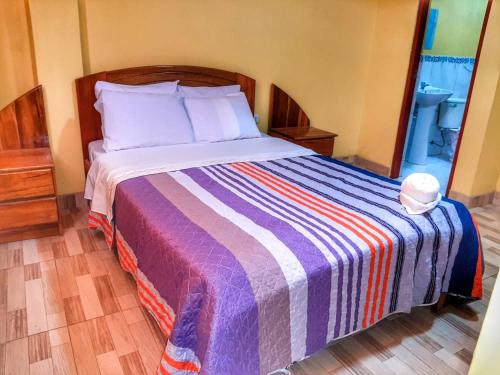 a bedroom with a bed with a colorful striped blanket at Hostal Kollarón in Chachapoyas