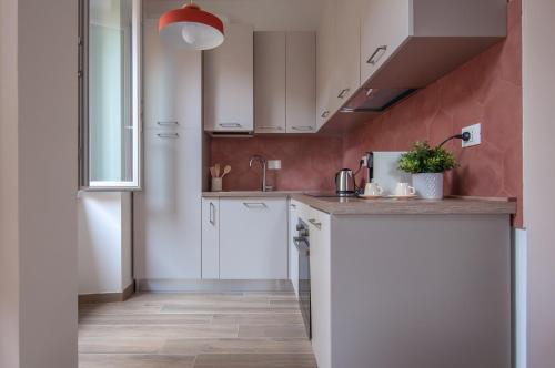 a kitchen with white cabinets and a red wall at Casa Matta in Castel Gandolfo