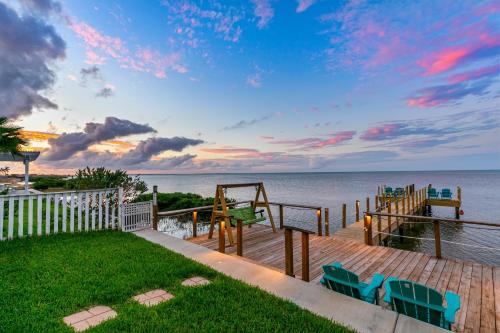 a deck with chairs and the ocean at sunset at Las Joyas Bayview Home in Port Isabel