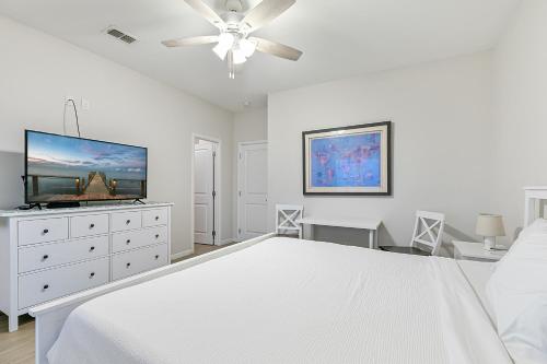 a white bedroom with a bed and a flat screen tv at Las Joyas Bayview Home in Port Isabel