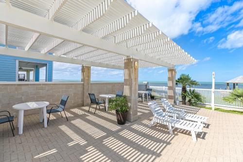 a patio with tables and chairs under a white pergola at Las Joyas Bayview Home in Port Isabel