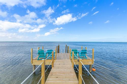 a wooden pier with blue chairs on the water at Las Joyas Bayview Home in Port Isabel