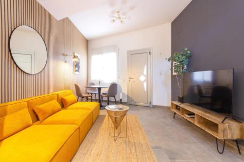 a living room with a yellow couch and a television at Duplex with terrace near Bcn in Terrassa